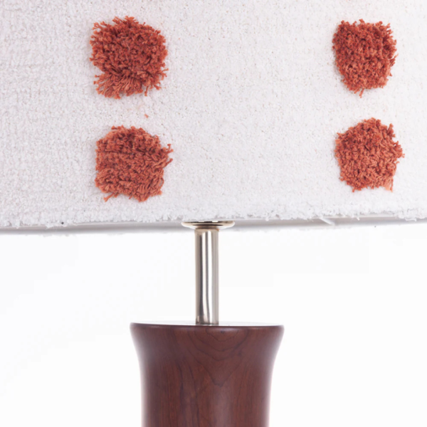 Abajur feito em madeira com base dos pés em formato cilíndrico com topos superiores e inferiores levemente achatados em tonalidade marrom, e cúpula de tecido tapeçaria em tonalidade branca e pontos felpudos em cor terracota. Peça de design elegante que agrega um diferencial a decoração. Bivolt, possui 01 soquete tipo E27, potência máxima de 60w e não acompanha lâmpada.