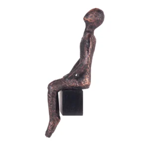 Escultura de resina na fisionomia de um homem sentando olhando para cima, sobre base também de resina com abertura para ser pendurada na parede. Adorno de acabamento rústico criado para ser exposto na parede com a escultura voltada para o lado esquerdo como se estivesse observando. Desenvolvido e fabricado nacionalmente pela Modali Design.