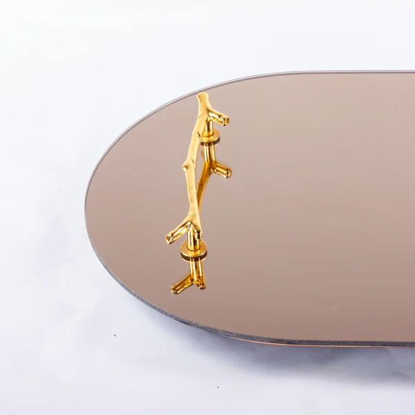 Bandeja feita de madeira revestida com espelho em sua base, com design em formato oval e elegante com detalhe de puxadores em metal dourado liso. Peça que agrega personalidade a decoração e pode ser utilizado sobre aparadores em salas e quartos. Desenvolvido e fabricado nacionalmente pela Modali Design.