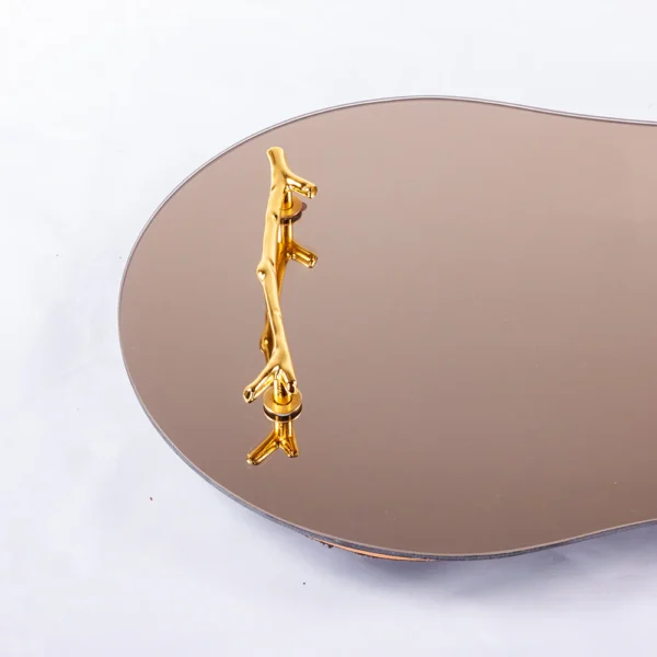 Bandeja feita de madeira revestida com espelho em sua base, com design em curvas sinuosas e elegantes com detalhe de puxadores em metal dourado liso. Peça que agrega personalidade a decoração e pode ser utilizado sobre aparadores em salas e quartos. Desenvolvido e fabricado nacionalmente pela Modali Design.