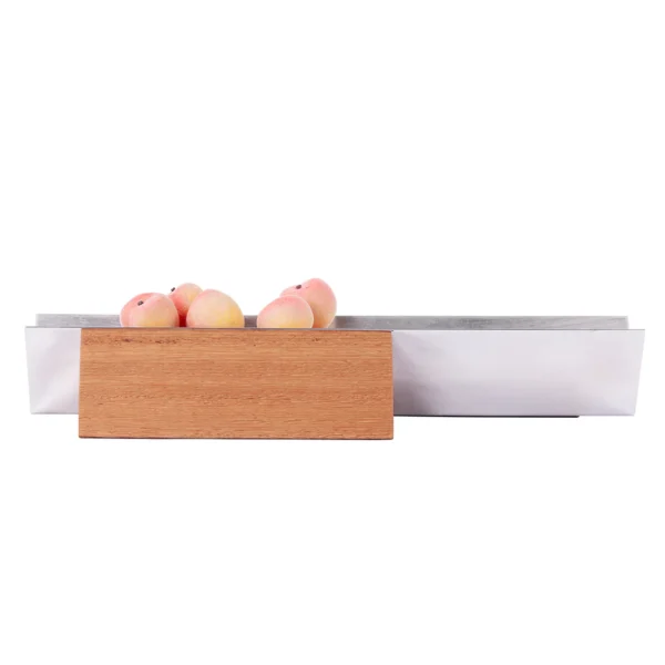 Vértice é uma fruteira que se apropria de uma forma geométrica simples, o triângulo. Formada por 3 elementos apenas, a proposta é manter as frutas justapostas em linha reta. O rigor e formalidade estão presentes em uma peça de acabamento esmerado e complexidades de montagem. Detalhe para o trabalho de polimento e escovamento do aço e para a madeira de Sucupira, reconhecida por sua dureza e alta densidade.