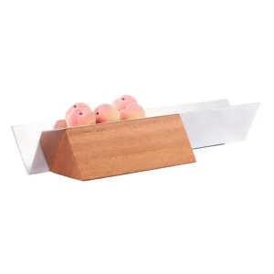 Vértice é uma fruteira que se apropria de uma forma geométrica simples, o triângulo. Formada por 3 elementos apenas, a proposta é manter as frutas justapostas em linha reta. O rigor e formalidade estão presentes em uma peça de acabamento esmerado e complexidades de montagem. Detalhe para o trabalho de polimento e escovamento do aço e para a madeira de Sucupira, reconhecida por sua dureza e alta densidade.