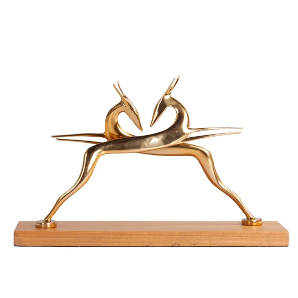 Escultura feita de alumínio em tonalidade dourada e com base de madeira natural, com desenho artístico de silhueta de dois bambis. Adorno de acabamento liso criado para ser exposto sobre mesas, aparadores, estantes e prateleiras. Desenvolvido e fabricado nacionalmente pela Modali Design.