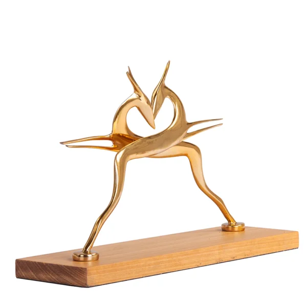 Escultura feita de alumínio em tonalidade dourada e com base de madeira natural, com desenho artístico de silhueta de dois bambis. Adorno de acabamento liso criado para ser exposto sobre mesas, aparadores, estantes e prateleiras. Desenvolvido e fabricado nacionalmente pela Modali Design.