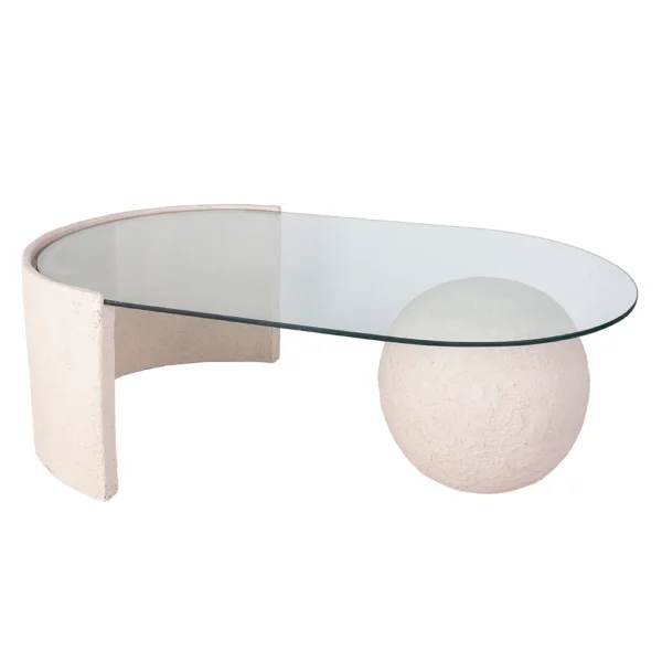 Mesa de centro feita em resina com tonalidade bege clara e com aspecto rústico e tampo de vidro incolor apoiado sobre base em formato de esfera em resina. Desenvolvido e fabricado nacionalmente pela Modali Design.