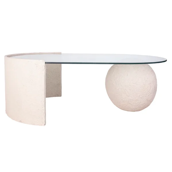 Mesa de centro feita em resina com tonalidade bege clara e com aspecto rústico e tampo de vidro incolor apoiado sobre base em formato de esfera em resina. Desenvolvido e fabricado nacionalmente pela Modali Design.
